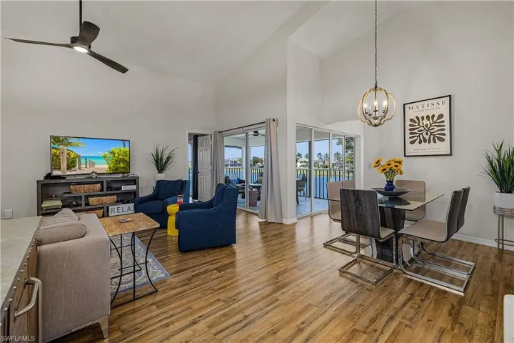 Living room with ceiling fan, wood finished floors, vaulted ceiling, and suspended lighting
