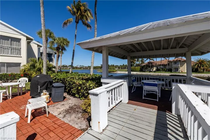 Wooden deck featuring a grill, a water view, outdoor dining space, and a patio