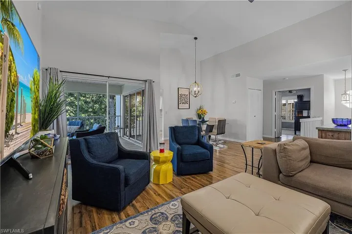 Living room with wood finished floors, suspended lighting, plenty of natural light, and lofted ceiling