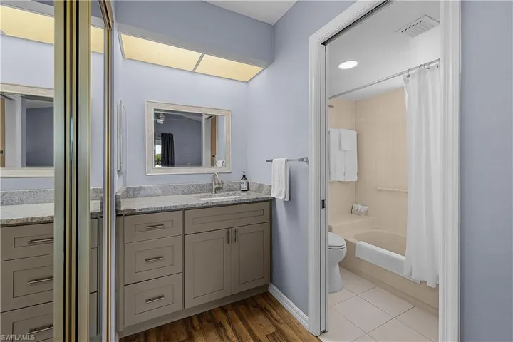Bathroom with vanity, shower / bath combo with shower curtain, and dark tile patterned floors