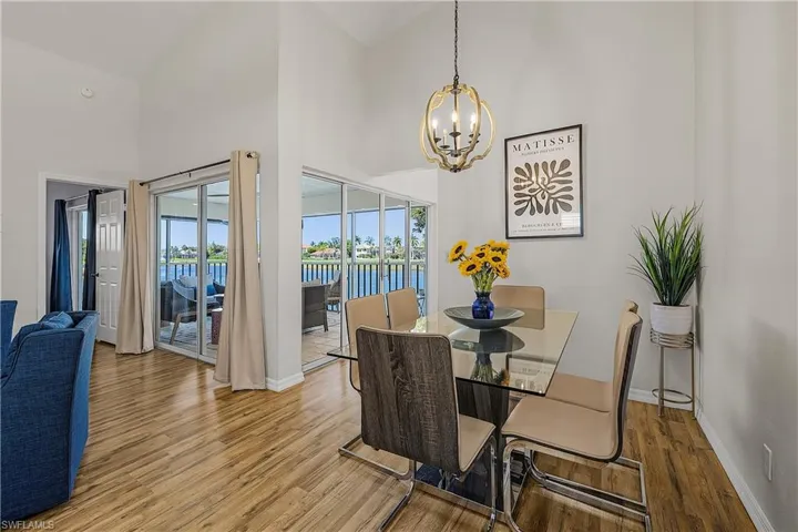 Dining space featuring hanging lights, wood finished floors, a water view, and vaulted ceiling