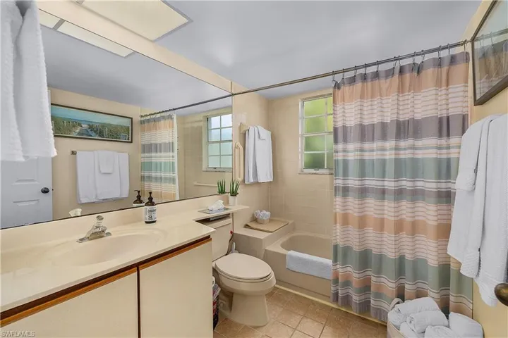Full bathroom with vanity, shower / bath combination with curtain, and light tile patterned flooring