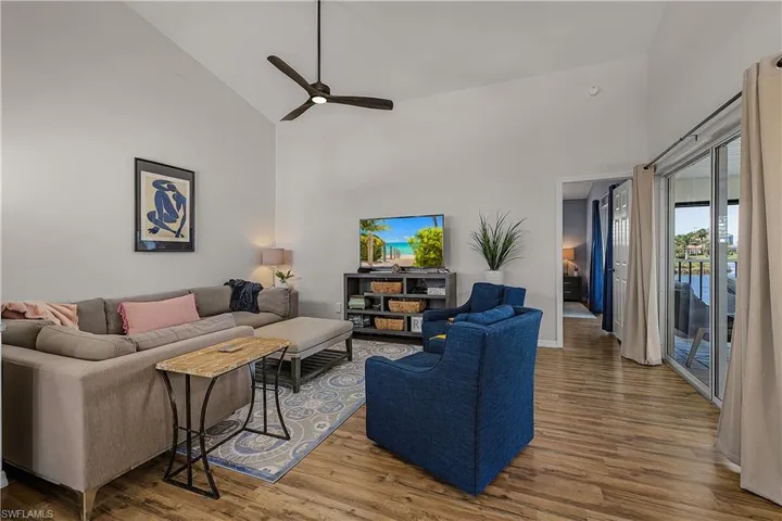 Living room with vaulted ceiling, ceiling fan, and wood finished floors