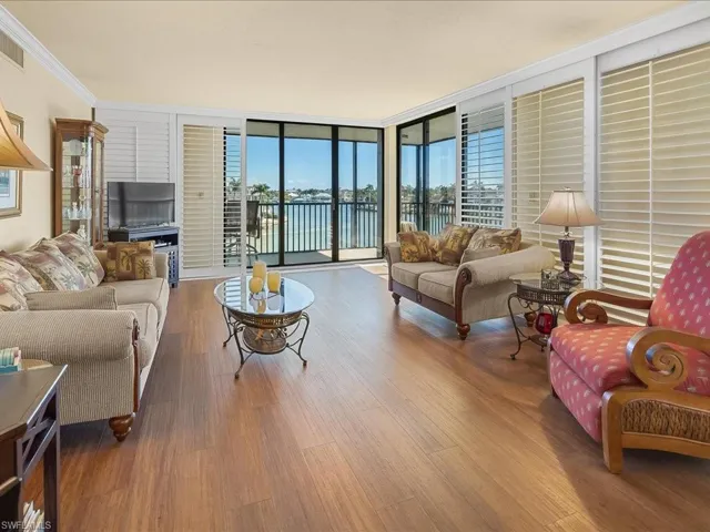 Spacious living Room with slider doors to wrap around balcony. plantation shutters, crown molding, and vinyl flooring