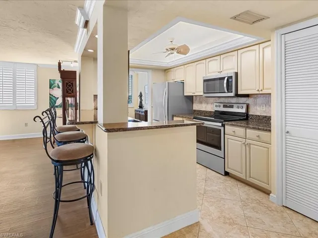 Kitchen with cream cabinetry, stainless steel appliances, dark stone countertops, ornamental molding, and recessed lighting