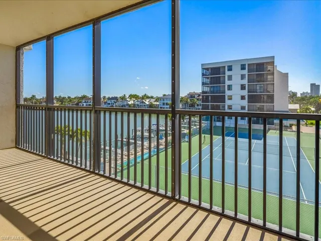 South facing balcony with a sunroom and view of the bay, pool, and tennis courts