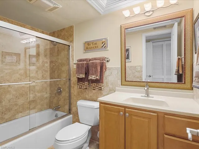 Second Full bathroom with vanity, enclosed tub / shower combo, tile walls and flooring, tray ceiling