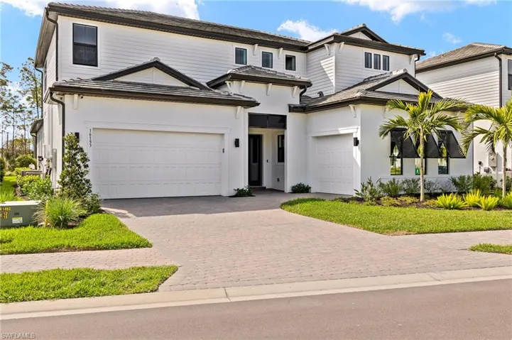 View of front facade featuring stucco siding, an attached garage, and decorative driveway