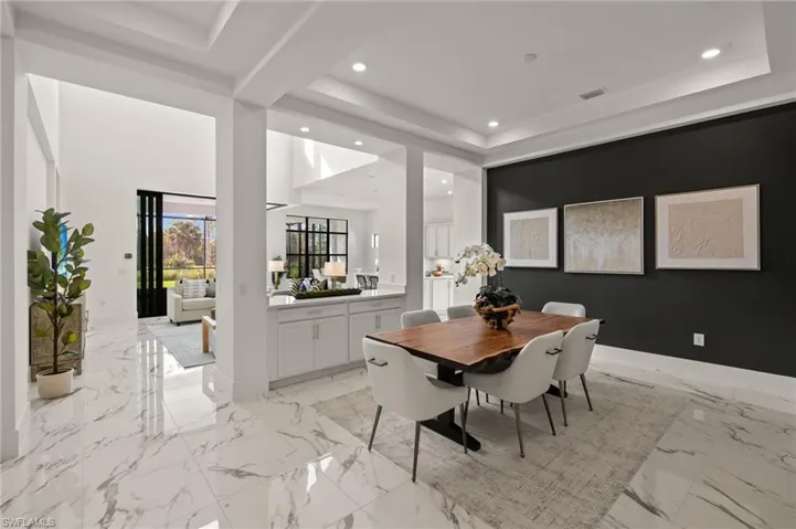 Dining area featuring marble finish floor, recessed lighting, and a tray ceiling