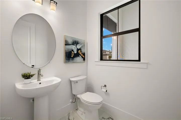 Half bath with baseboards, toilet, and marble finish floor