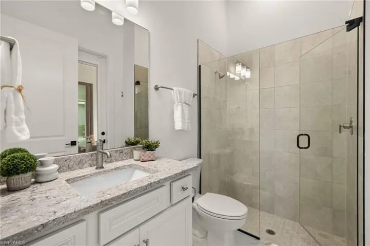 Bathroom featuring a shower stall, vanity, and toilet
