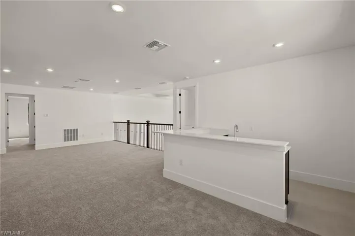 Empty room featuring light colored carpet, visible vents, and recessed lighting