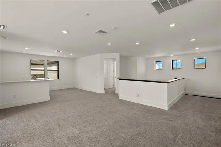 Empty room featuring light colored carpet, visible vents, baseboards, and recessed lighting