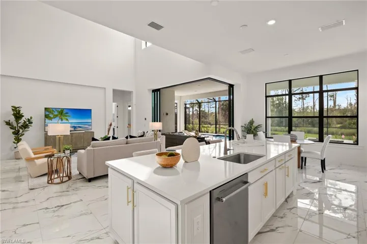 Kitchen with stainless steel dishwasher, marble finish floor, a sink, light countertops, and white cabinets