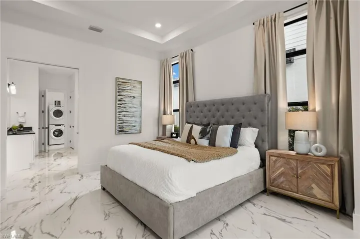 Bedroom featuring stacked washing maching and dryer, visible vents, marble finish floor, and recessed lighting