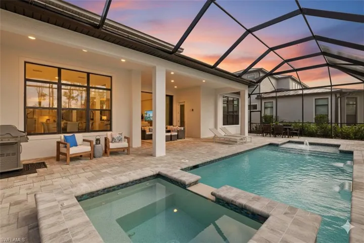View of swimming pool featuring a pool with connected hot tub, a patio, a sunroom, a lanai, and area for grilling