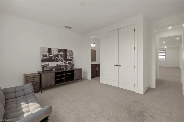 Living area with light carpet, visible vents, and baseboards