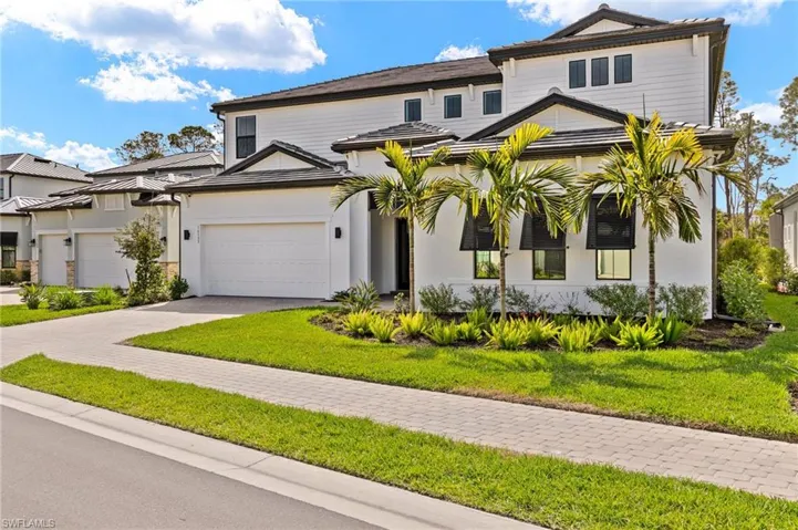 View of front of property with an attached garage, decorative driveway, and a front lawn