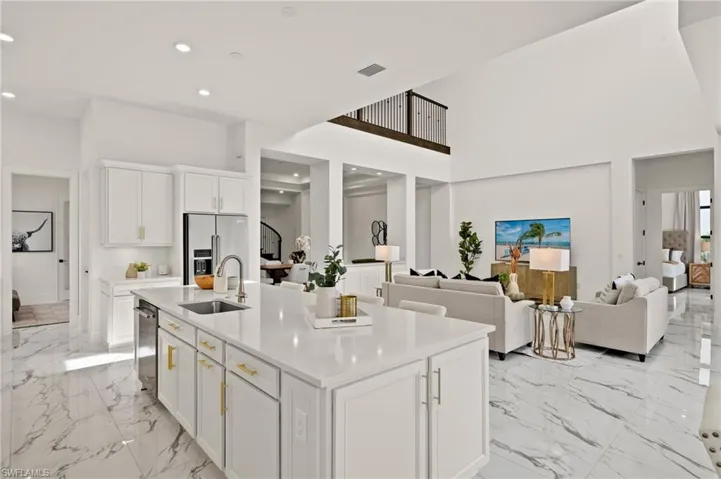 Kitchen with a sink, light countertops, a kitchen island with sink, stainless steel appliances, and white cabinets
