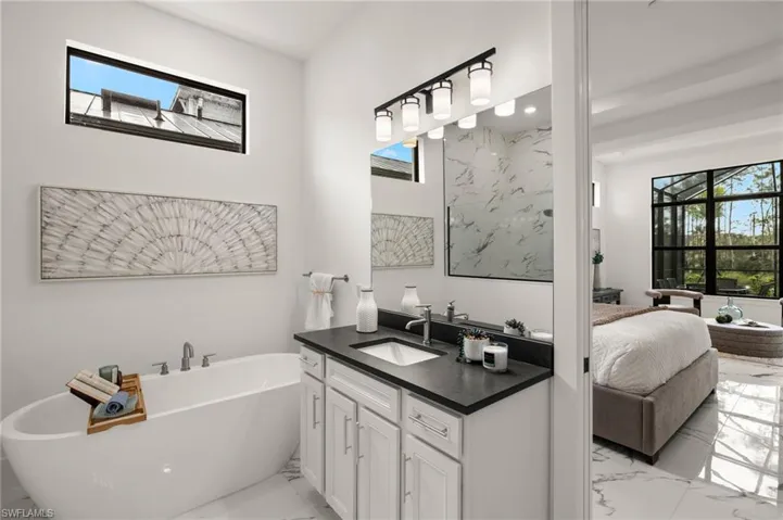 Ensuite bathroom with marble finish floor, vanity, a freestanding tub, and ensuite bath