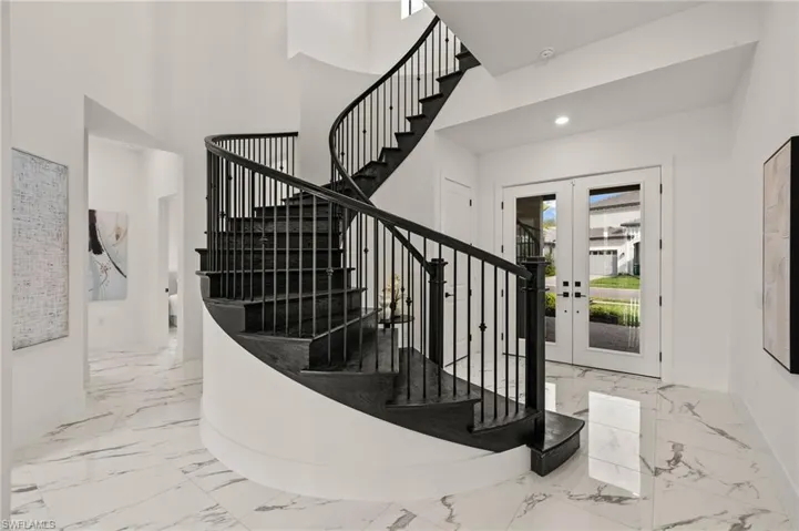 Staircase with baseboards, marble finish floor, a high ceiling, recessed lighting, and french doors