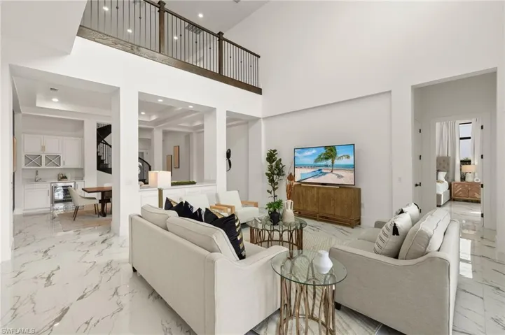 Living room featuring marble finish floor, stairs, a towering ceiling, and recessed lighting