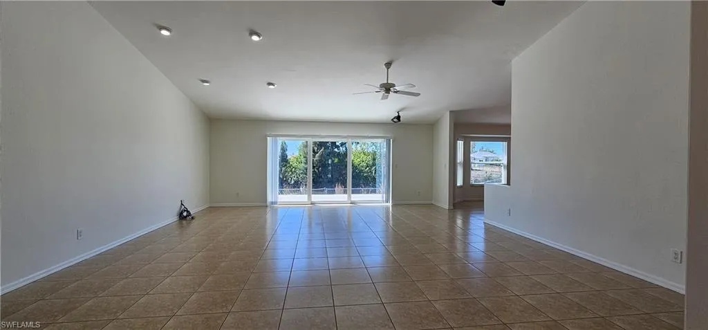 Unfurnished room with a ceiling fan, vaulted ceiling, and light tile patterned floors