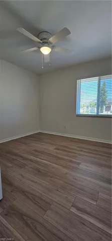 Empty room with dark wood-style flooring and ceiling fan