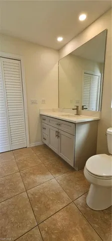 Bathroom featuring a closet, vanity, light tile patterned floors, and recessed lighting