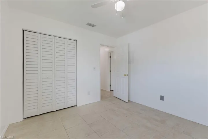 Unfurnished bedroom featuring a closet, ceiling fan, and light tile patterned floors