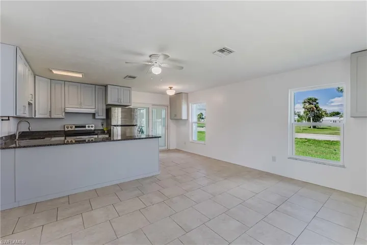 Kitchen featuring dark stone counters, ceiling fan, a peninsula, stainless steel appliances, and gray cabinets