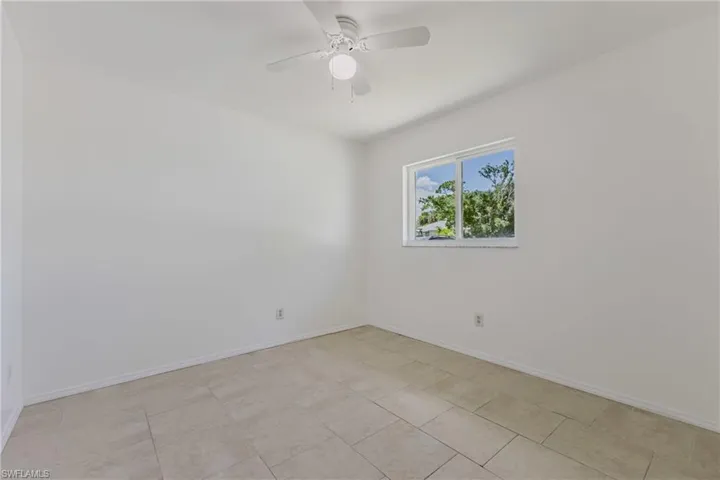 Empty room featuring a ceiling fan and baseboards