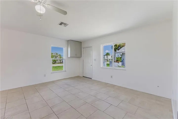 Unfurnished room with healthy amount of natural light, ceiling fan, and light tile patterned flooring