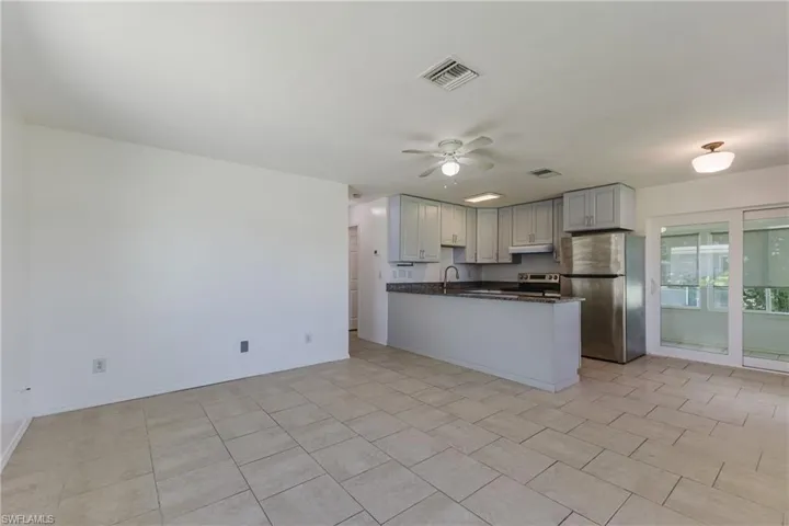 Kitchen featuring stainless steel appliances, ceiling fan, dark stone countertops, a peninsula, and open floor plan
