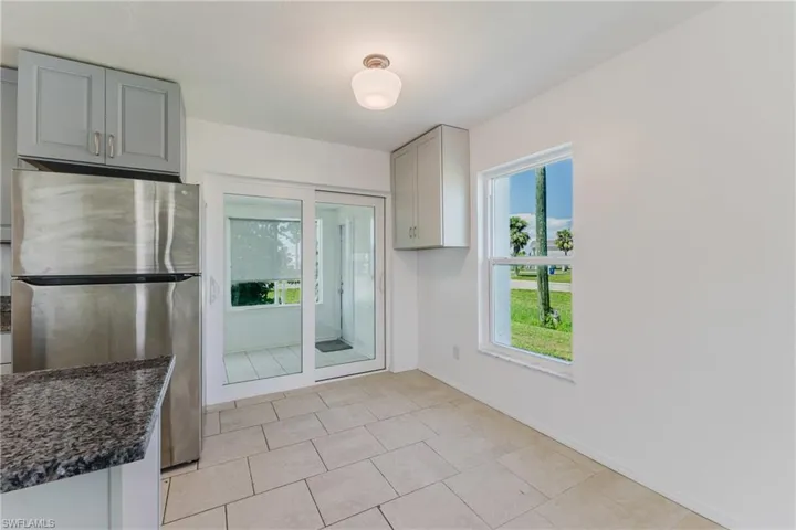 Kitchen featuring freestanding refrigerator, gray cabinetry, dark stone counters, and light tile patterned flooring