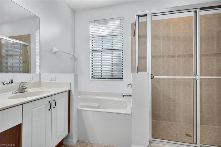 Full bath with a stall shower, vanity, a garden tub, and light tile patterned floors
