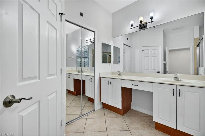 Bathroom with double vanity, a chandelier, and light tile patterned floors