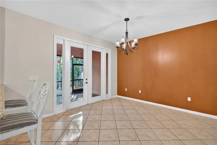 Unfurnished dining area featuring french doors, a chandelier, and light tile patterned floors