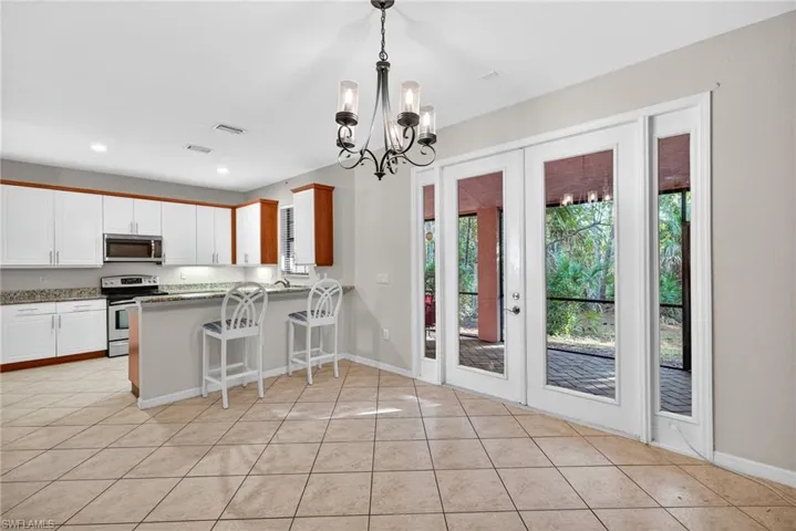 Kitchen with a kitchen breakfast bar, french doors, stainless steel appliances, and white cabinetry