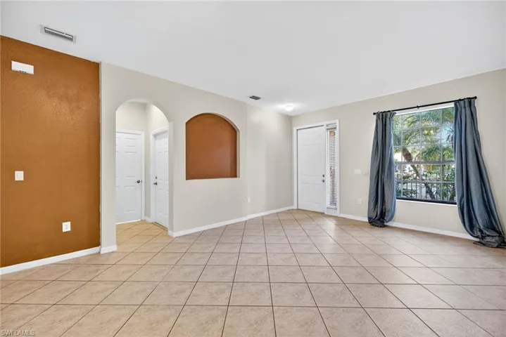 Empty room with arched walkways and light tile patterned floors