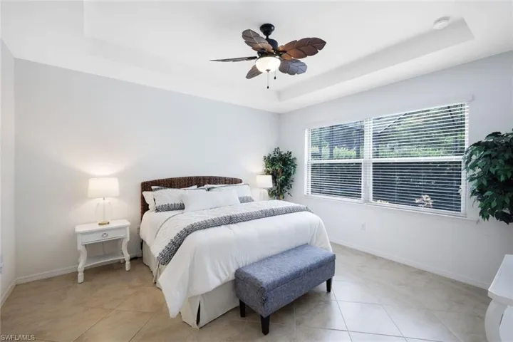 Tiled bedroom featuring ceiling fan and a raised ceiling