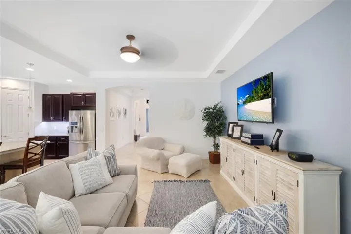 Tiled living room featuring a raised ceiling and ceiling fan