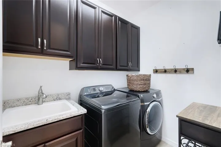 Laundry room with mud sink, add'l cabinetry and washer/dryer.