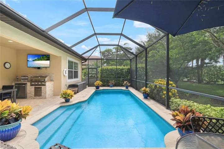 View of pool featuring a patio area, an outdoor kitchen, a lanai, and grilling area