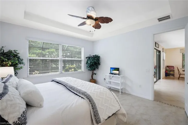 Bedroom featuring light tile patterned floors, ceiling fan, and a raised ceiling
