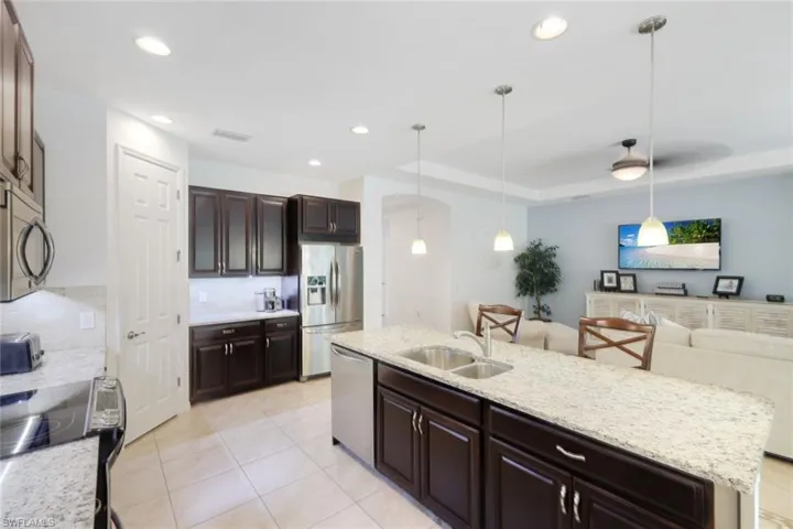 Kitchen with tasteful backsplash, a kitchen island with sink, stainless steel appliances, hanging light fixtures, and sink