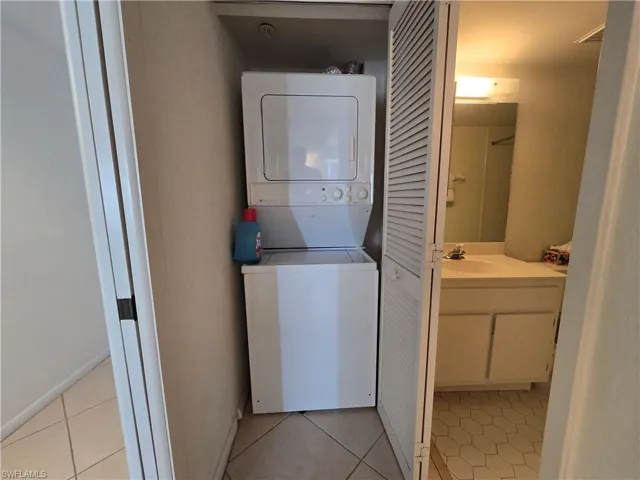 Laundry room featuring stacked washer / dryer and light tile patterned floors