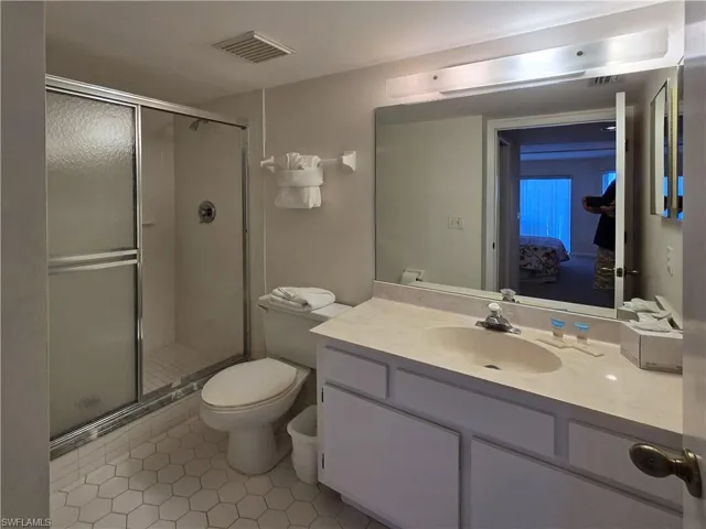 Primary bathroom featuring tile patterned floors, a shower stall, vanity, and ensuite bathroom