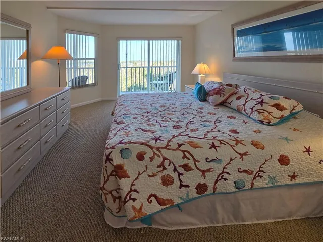 Carpeted primary bedroom with access to exterior and baseboards