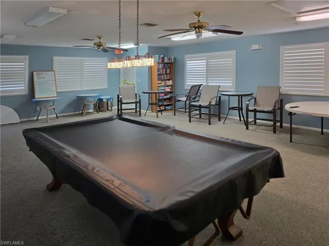 Clubhouse  featuring carpet, ceiling fans, pool billiard table, books, games and chairs and tables  to spend time  with family and friends
